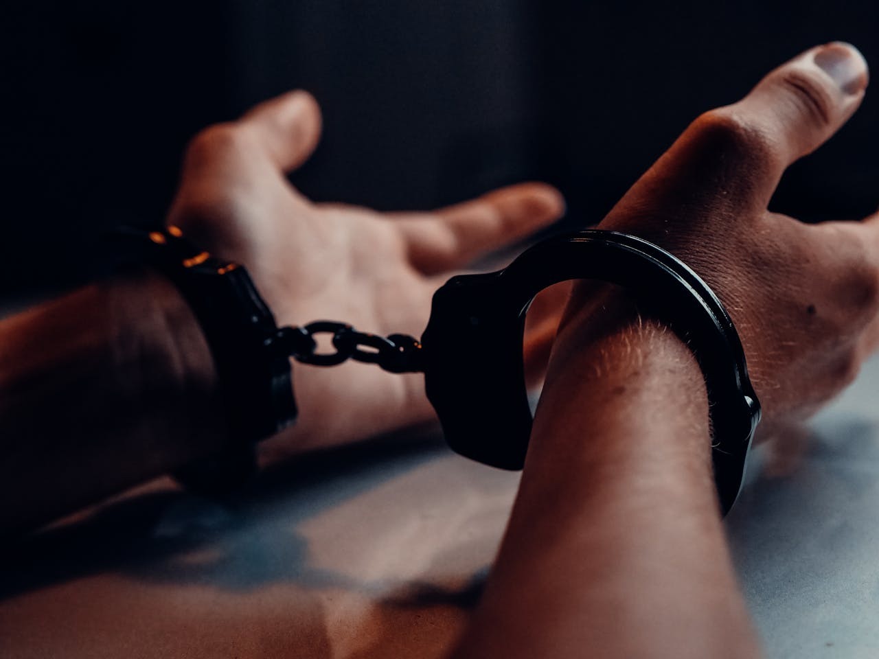 Close-up of hands in handcuffs on a table, symbolizing DUI arrest and penalties in Pennsylvania.